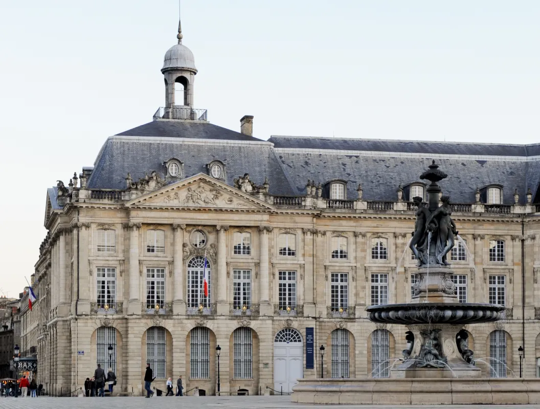 Cette photo met en avant la place de la Bourse. La fontaine des Trois Grâces est présente sur la photographie également.